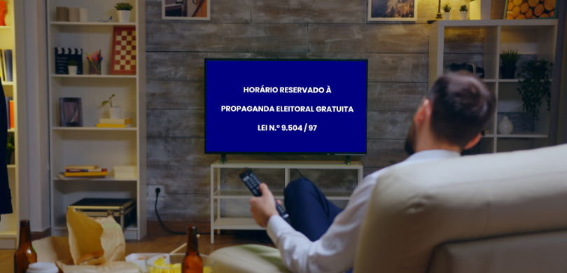 Fotografia em que se observa, em primeiro plano e de costas, um homem sentado em um sofá bege, s...